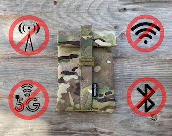 May include: A camouflage fabric pouch with a black strap and buckle. The pouch has the text "SHRUIGGEAR" printed on the strap. The pouch is surrounded by red circles with black symbols representing no signal, no wifi, no 5G, and no bluetooth.