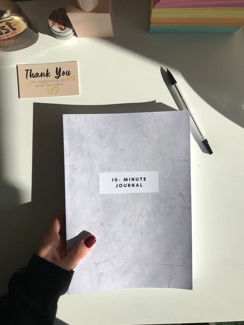 May include: A grey journal with a white label that says "10-Minute Journal". The journal has a textured surface that resembles concrete.