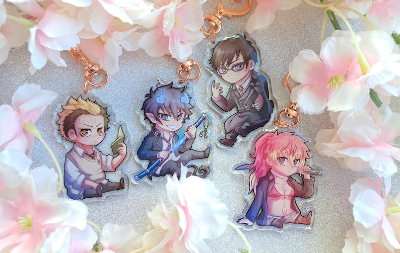 Peut inclure: Quatre porte-cl&eacute;s de personnages d'anime avec des fonds en acrylique transparent. Les personnages sont un gar&ccedil;on blond avec un livre, un gar&ccedil;on aux cheveux bleus avec une &eacute;p&eacute;e, un gar&ccedil;on aux cheveux bruns et aux lunettes, et une fille aux cheveux roses avec un couteau.