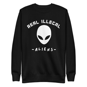 May include: Black sweatshirt with white text that reads "REAL ILLEGAL ALIENS" and a white alien head graphic.