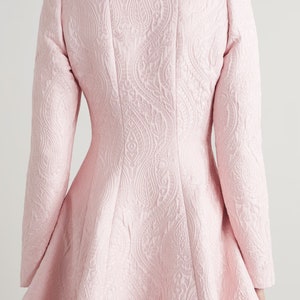 May include: A pink, long-sleeved dress with a paisley pattern. The dress has a fitted bodice and a flared skirt.