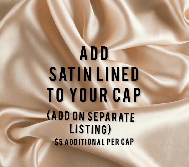 以下が含まれることがあります： ベージュのサテン生地のクローズアップで、「ADD SATIN LINED TO YOUR CAP」というテキストが入っています。生地はドレープされており、柔らかい折り目があります。テキストは太字の黒色です。