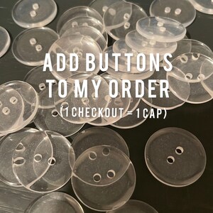 May include: A collection of clear, transparent buttons with two or four holes, scattered across a dark surface. The text "ADD BUTTONS TO MY ORDER" is overlaid on the image.