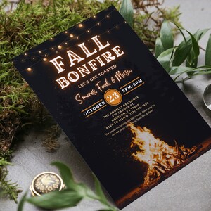 May include: A black invitation card with the words "FALL BONFIRE" in a glowing orange font, along with details for an event including the date, time, and location. The card features a bonfire illustration at the bottom and string lights at the top.