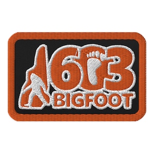May include: Orange and white embroidered patch with the text "613 BIGFOOT" and a white silhouette of a Bigfoot walking to the left.