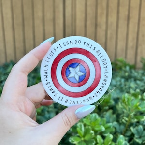 May include: A round sticker featuring a shield design in red, white, and blue, with a star in the center. The sticker has the text "I CAN DO THIS ALL DAY. LANGUAGE WHATEVER IT TAKES. WALK IT OFF." The sticker is held by a hand.