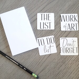 May include: Four white square stickers with black text. The stickers say "The List", "Work of Art", "To Do List", and "Don't Forget".