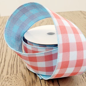 May include: A roll of decorative ribbon with a reversible design. One side features a red and white gingham pattern, while the other side is a light blue plaid. The ribbon is ideal for crafts, gift wrapping, and seasonal decorations.