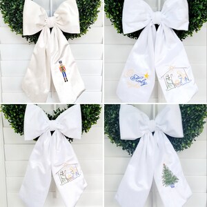 Puede incluir: Cuatro lazos de satén blanco con diferentes diseños bordados. Los diseños incluyen un cascanueces, una escena de la natividad, las palabras "Holy Night" y un árbol de Navidad.