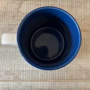 Puede incluir: Una taza de cer&aacute;mica azul con un asa blanca. La taza est&aacute; vac&iacute;a y el interior es visible.