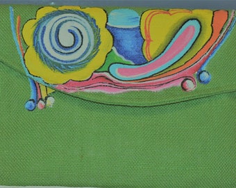 May include: A green canvas clutch bag with a colorful abstract design painted on the front. The design features swirls, circles, and lines in shades of yellow, blue, pink, and orange.
