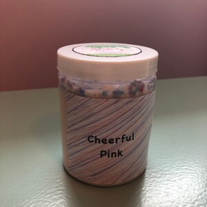 May include: A clear jar of pink slime with a white lid and a label that says "Cheerful Pink".