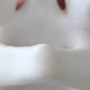 May include: Close-up of a white ceramic planter with a smooth, rounded rim. The planter has a slightly textured surface and a small opening at the bottom for drainage.
