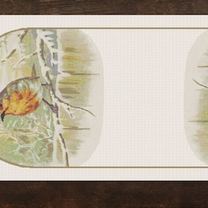 Op de afbeelding: Een witte rechthoekige tafelrunner met twee ovale ontwerpen. Elk ontwerp toont een bruine vogel met oranje en gele veren die op een tak zit in een besneeuwde bosomgeving.