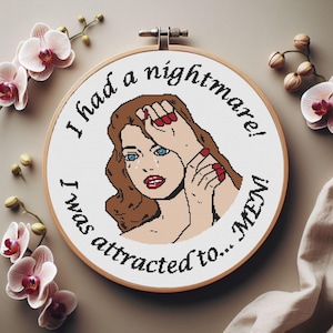 May include: A cross-stitch hoop featuring a pop art style image of a woman with brown hair and blue eyes, crying. The text around the image reads "I had a nightmare! I was attracted to... MEN!" The woman has red lipstick and red fingernails.