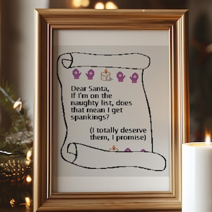 May include: Framed cross-stitch art with a gold-colored frame. The artwork features a scroll design with the text "Dear Santa, If I'm on the naughty list, does that mean I get spankings? (I totally deserve them, I promise)".