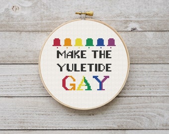 May include: A white embroidery hoop with a cross-stitch design that reads "Make the Yuletide Gay". The design features a rainbow of colours and a row of bells at the top.