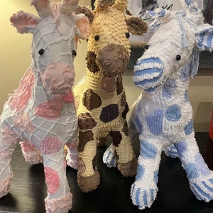 May include: Three plush giraffe toys, one pink with white, one tan with brown spots, and one blue with white stripes.