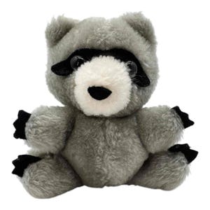Könnte beinhalten: Ein graues Plüsch-Waschbär-Spielzeug mit schwarzen Akzenten um Augen, Pfoten und Füße. Der Waschbär hat eine weiße Schnauze und eine schwarze Nase. Das Spielzeug sitzt aufrecht mit ausgestreckten Armen.