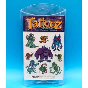 May include: A clear plastic package containing two sheets of temporary tattoos featuring colorful cartoon monsters, snakes, and insects. The package is labeled "Temporary Taticoz 2 Different Sheets of Temporary Tattoos".