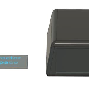 May include: A dark grey rectangular box with rounded corners and a matching rectangular label. The label reads "30 character total space" in light blue text. The box has a recessed front panel.