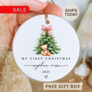 May include: White ceramic Christmas ornament with a watercolor illustration of a Christmas tree, teddy bear, and a red and white plaid bow. Text reads "My First Christmas" and "Sophia Rose 2025". Includes a gold string for hanging.