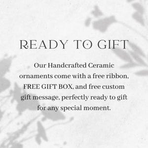 May include: Text on a white background reads "READY TO GIFT." Below, it states that handcrafted ceramic ornaments come with a free ribbon, gift box, and custom gift message. The text is in a serif font.