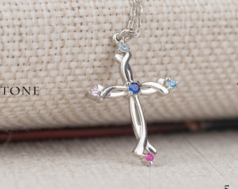 May include: Silver necklace with a cross pendant featuring five birthstones. The birthstones are set in the cross and are in various colours, including blue, pink, and white.