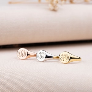 Könnte beinhalten: Drei Siegelringe mit unterschiedlichen Gravuren. Die Ringe sind aus Gold, Silber und Roségold. Die Gravuren sind alle gleich, mit den Buchstaben "ERM" in einer Schriftart.