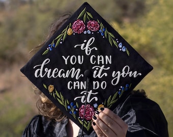 May include: Black graduation cap with embroidered flowers and the text "if you can dream it you can do it".