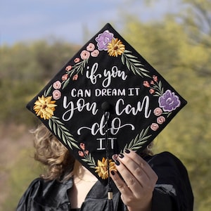 Könnte beinhalten: Schwarze Abschluss-Kappe mit Blumenstickerei und dem Text "if you can dream it you can do it".