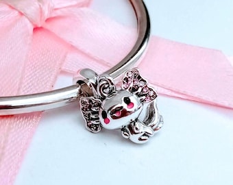 Puede incluir: Un charm de plata con un diseño de ajolote con detalles en rosa. El ajolote tiene detalles de gemas rosas en sus branquias y cabeza, con boca rosa y ojos negros. El charm está unido a una pulsera de plata, con una cinta rosa en el fondo.