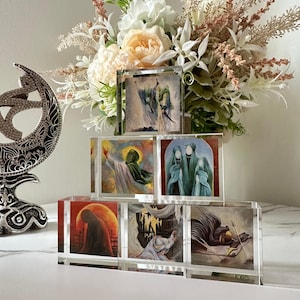 May include: A set of six glass blocks with colorful images of religious figures. The blocks are stacked in a pyramid shape and are displayed on a white surface.