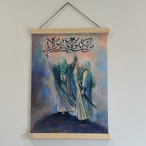 Può includere: Un'opera d'arte murale verticale con un'illustrazione di due figure in abiti fluenti, una con una spada. L'opera presenta calligrafia araba in alto ed è incorniciata con legno naturale.