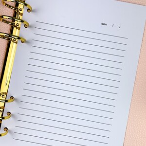 Pu&ograve; includere: Una pagina bianca rigata in un raccoglitore ad anelli dorati con la parola "data" scritta in alto.