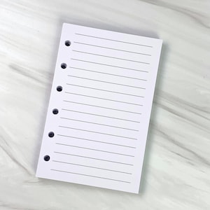 May include: A white lined paper pad with eight punched holes on the left side. The paper is blank and ready for writing.