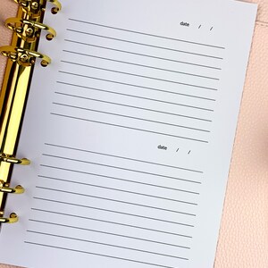 May include: A white page with lined paper and the word "date" written at the top and bottom of the page. The page is in a binder with gold rings.
