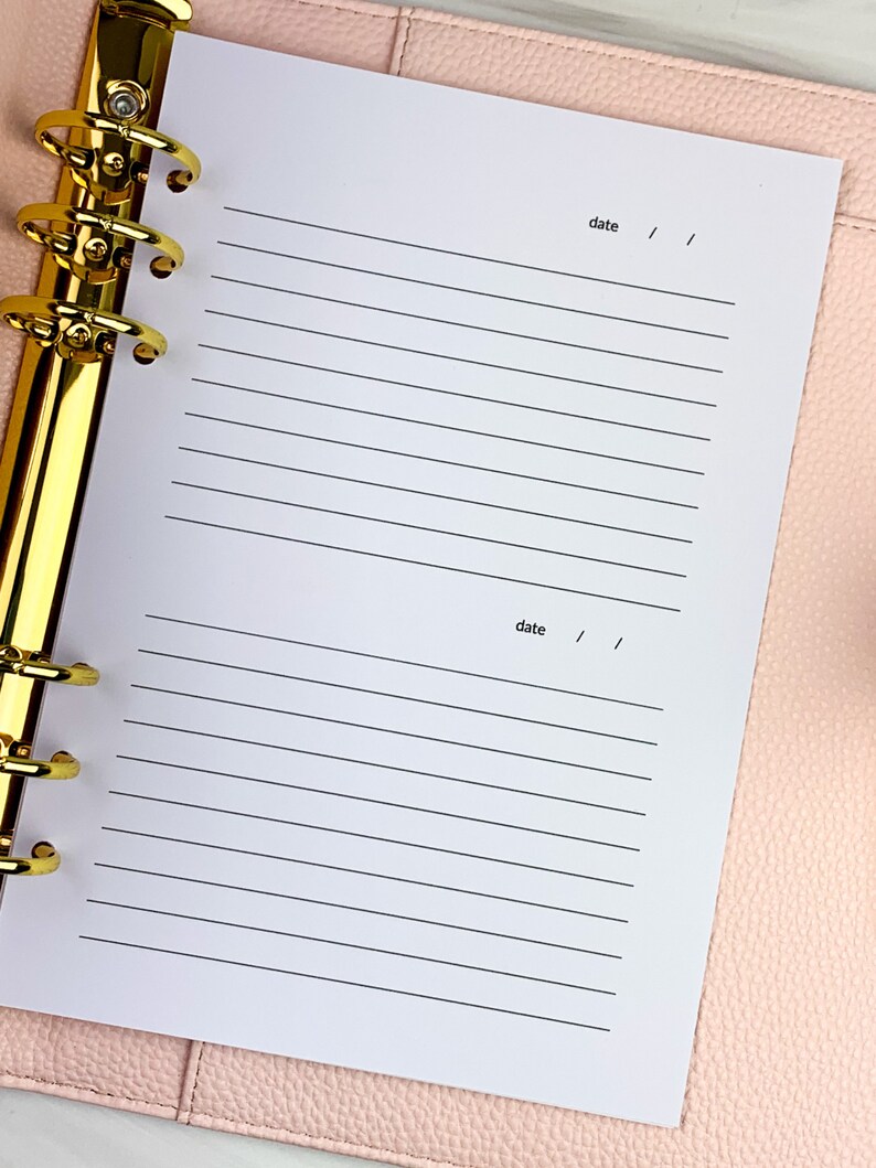 May include: A white page with lined paper and the word "date" written at the top and bottom of the page. The page is in a binder with gold rings.