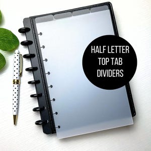 May include: Black binder with clear half-letter top tab dividers. A white pen with black polka dots and gold accents is next to the binder. The text "HALF LETTER TOP TAB DIVIDERS" is on a black circle.