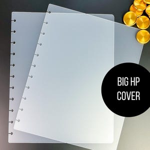 May include: Two clear plastic covers for a large disc bound planner. The covers are stacked on top of each other and have a row of holes down the left side. The text "BIG HP COVER" is printed in black on a black circle.
