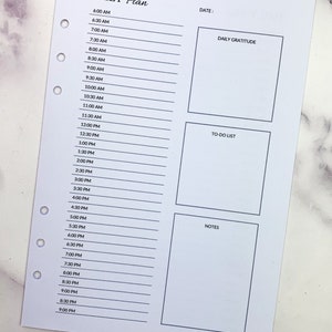 May include: A daily planner with sections for daily gratitude, to-do list, and notes. The planner has a time slot for each hour from 6:00 AM to 9:00 PM.