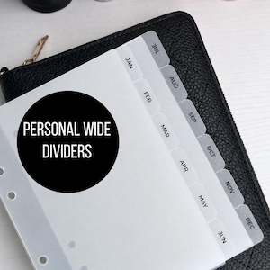 May include: White personal wide dividers with monthly tabs labeled January through December. The dividers are on top of a black quilted leather wallet. The text "PERSONAL WIDE DIVIDERS" is in a black circle.