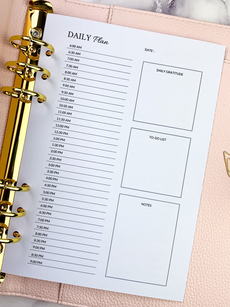May include: A daily planner with a white background and black text. The planner has sections for daily gratitude, to-do list, and notes. The planner is divided into hourly time slots from 6:00 AM to 9:00 PM.