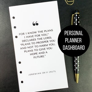 May include: A white planner dashboard with a quote from Jeremiah 29:11, a black and white polka dot pen, and a gold paperclip on a black surface. The text on the dashboard reads "For I know the plans I have for you..."
