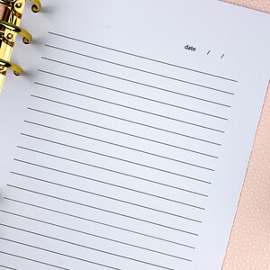 Pu&ograve; includere: Un quaderno bianco a righe con un raccoglitore dorato e la parola "data" scritta in cima alla pagina.