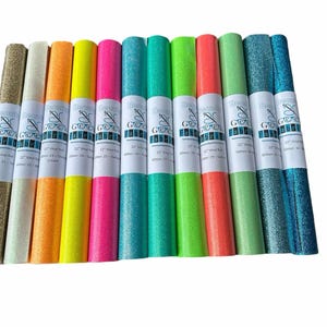 Puede incluir: Diez rollos de vinilo con purpurina de 30,5 cm de ancho en varios colores, incluyendo dorado, blanco, naranja, amarillo, rosa, turquesa, verde, verde lima, coral y verde claro. Cada rollo tiene una etiqueta con el texto "The Vinyl Gurus" y el tama&ntilde;o y el color del vinilo.