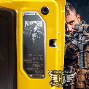 May include: A yellow vehicle door panel with a metal plate featuring a Punisher graphic and the text "MADE IN THE U.S.A." and "If You Want PEACE Prepare for WAR." The image also shows a person holding a rifle.