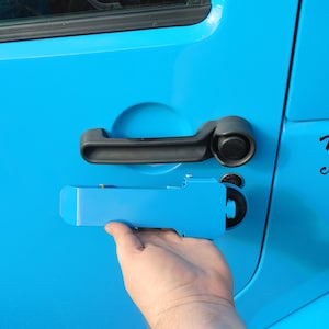 May include: A blue car door with a black door handle and a blue plastic door handle. The door handle is in the open position.