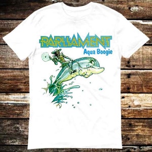 May include: White t-shirt featuring a cartoon character riding a dolphin. The text "Parliament Aqua Boogie" is printed on the shirt.