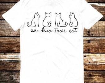 Könnte beinhalten: Weißes T-Shirt mit einer schwarzen Umrandung von drei Katzen und dem Text "un deux trois cat".